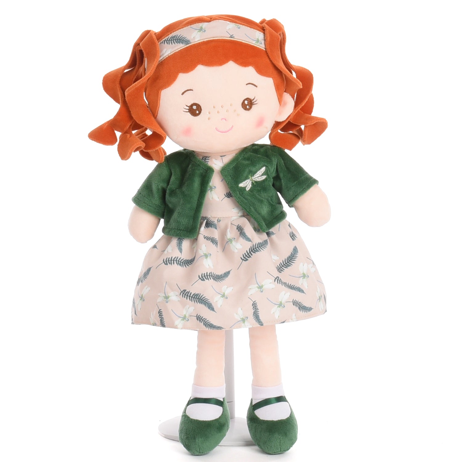 A plush doll with bright red curly hair, wearing a green cardigan and a beige dress with a green leaf pattern, standing against a plain white background.